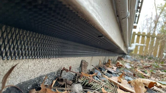 Custom galvanized mesh dig barrier installed along the base of a house